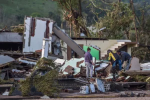 Marcos Gomes, second from right, searches for belongings at the site of his destroyed home after floods caused by a cyclone in Mucum. [Wesley Santos/AP Photo]